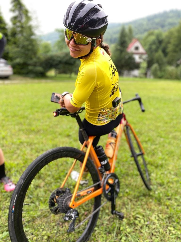 Ministra Kolarstwa oparta o pomarańczowy rower szosowy marki Trek