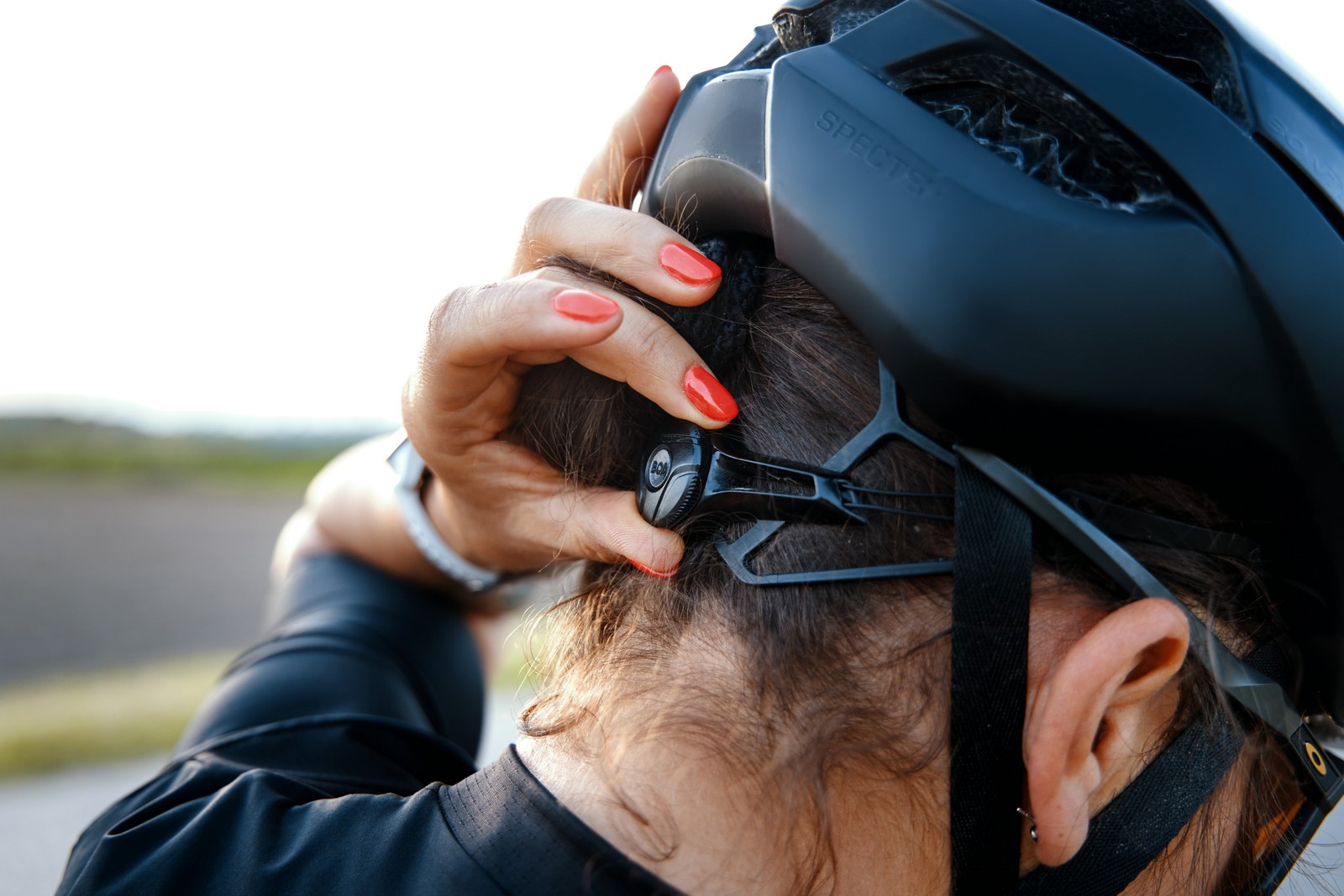 Na zdjęciu widać głowę w kasku rowerowym i pokrętło regulacji kasku, czyli tego jak ściśle przylega on do głowy