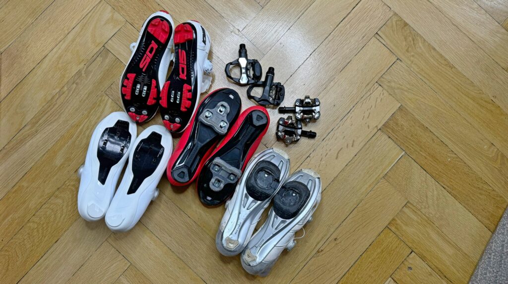 na zdjęciu widać kilka par butów rowerowych i cztery pary różnych typów pedałów nazywanych zatrzaskowymi - zdjęcie