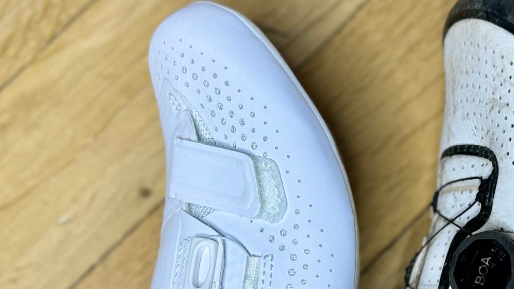 na zdjęciu widać czubek białego kolarskiego buta szosowego z akcentem na rzep, który nie zapina się do końca