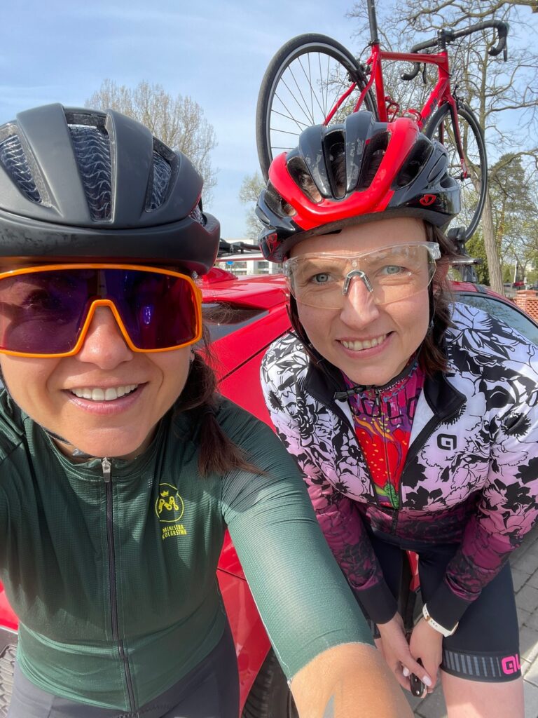 na zdjęciu są dwie kolarki ubrane w kaski i ubrania kolarskie, jedna z nich jest kursantką na szkoleniu na rowerze szosowym podczas szkolenia indywidualnego u Ministry Kolarstwa